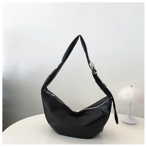 Detail of minimalist black hobo bag with silver zipper and wide adjustable strap
