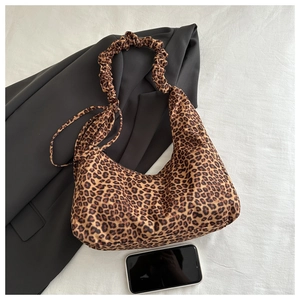 Detail of leopard print shoulder bag with ruched handle next to a smartphone for size scale