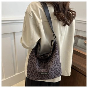 Close-up of leopard print tote bag featuring black leather strap and brand label detail