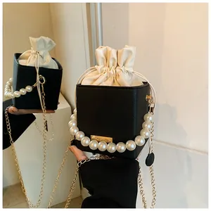 Detail of bicolored bucket bag with pearl handle and golden chain reflecting in mirror
