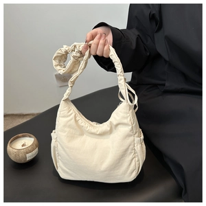Detail of beige nylon cloud bag featuring scrunchie pleat strap and side pockets