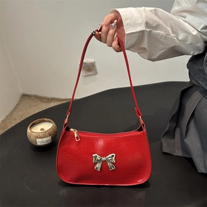 Red glossy faux leather underarm bag featuring a silver bow accent and minimalist design