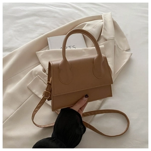 Detailed close-up of a caramel brown leather crossbody bag with gold hardware and top handle