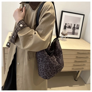 Close-up of leopard print suede tote bag with brand label worn on shoulder over trench coat