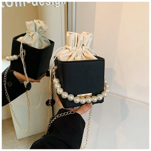 Detail of black crocodile texture bucket bag with pearl handle and golden chain