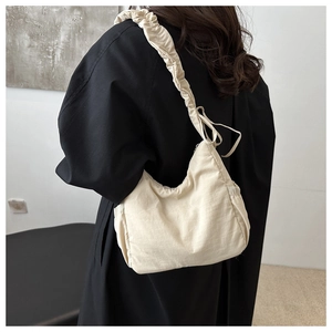Detail of beige nylon hobo bag with pleated shoulder strap and adjustable bow detail