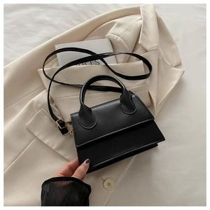Detail of a black leather handbag on a beige blazer with a vintage fashion book