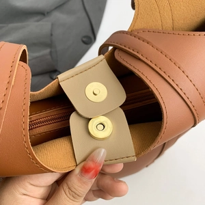 Minimalist brown leather tote bag featuring a secure magnetic closure and spacious interior