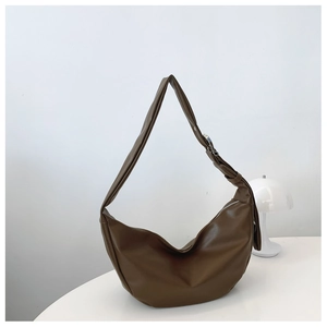 Detail of dark brown hobo bag with adjustable strap and silver buckle on white background