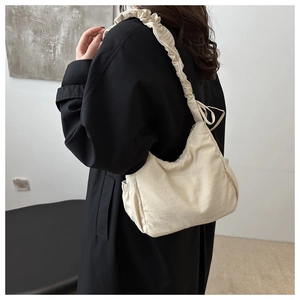 Detail of cream pleated shoulder strap on large crescent tote bag with cloud texture