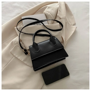 Detail of a chic black leather handbag with curved handles and an adjustable strap