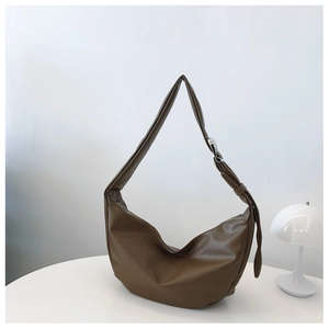 Brown hobo shoulder bag in soft PU leather with adjustable silver buckle on white table