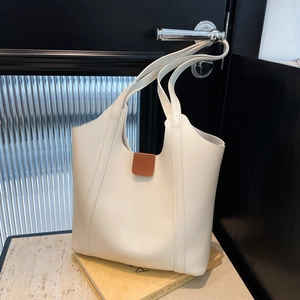 Minimalist cream tote bag with vertical stitching on handle in a lifestyle interior setting