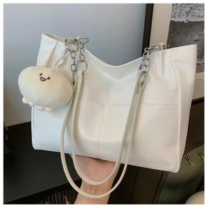 Detail of white PU leather tote with silver metal chain strap and plush ball charm