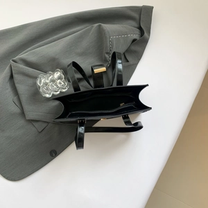 Schicke Handtasche aus schwarzem Lackleder mit goldenem Metallverschluss für modernes Styling