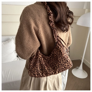 Close-up of leopard print hobo bag with unique pleated shoulder strap on model