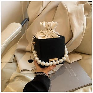 Detail shot of black leather bucket bag with pearl handle and gold accents