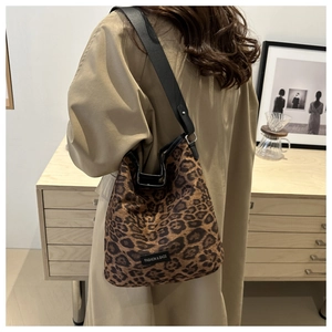Leopard print hobo bucket bag styled with black wide shoulder strap on a model
