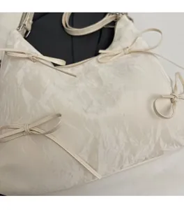 Détail du sac blanc texturé avec décorations de nœuds et imprimé Fashion argenté