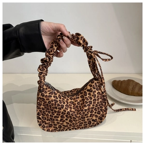 Detail of leopard print baguette bag featuring a ruched handle and tied ribbon accents
