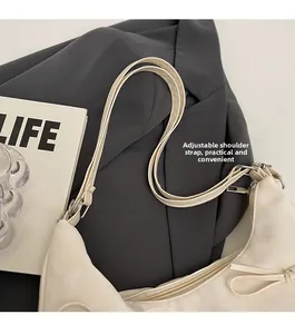Détail montrant la bandoulière réglable et le nœud latéral du sac fourre-tout crème