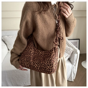 Close-up of leopard print canvas shoulder bag with pleated handle on female model