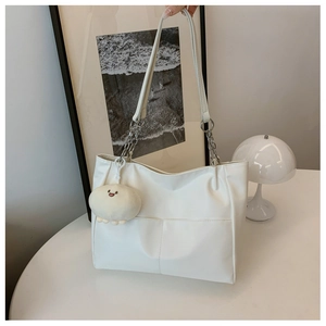 Detail of white tote bag with silver chain strap and cute smiley face plush charm