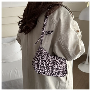 Close-up of leopard print baguette bag with knotted strap on beige trench coat