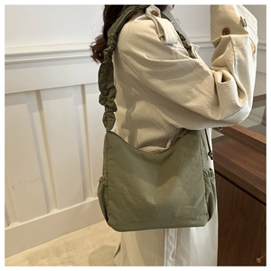 Close-up of army green nylon cloud bag featuring pleated wide shoulder strap and drawstring detail