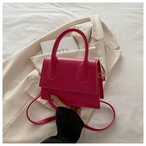 Magenta mini crossbody handbag in matte PU leather displayed on an ivory blazer jacket