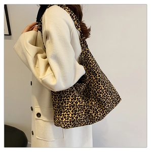 Close-up of leopard print tote bag with soft texture carried by model in a white coat