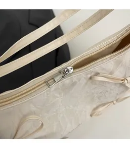 Détail d'une fermeture éclair argentée sur un sac à bandoulière plissé blanc crème