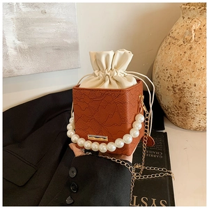 Detailed shot of textured crossbody bag with pearl handle and golden chain strap