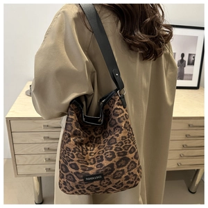 Detailed side view of leopard print bucket bag with wide black leather shoulder strap