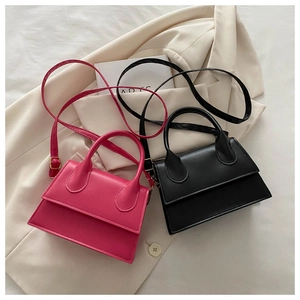 Detail of mini trapezoid handbags in rose pink and black on a beige blazer background