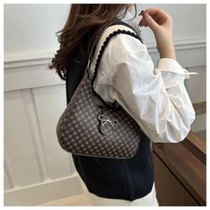 Detailed side view of a brown crescent shoulder bag with vintage pattern and metal bow