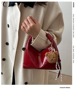 Close-up of red semicircular tote bag featuring a bear charm and striped ribbon detail