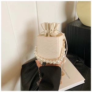 Detail of white bucket bag with floral lace embossing and large pearl handle