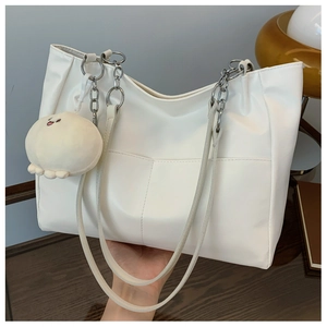 Close-up of white tote bag with silver chain handle and cute plush charm detail