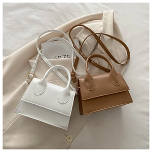 Detail of mini leather crossbody bags in white and brown with gold hardware