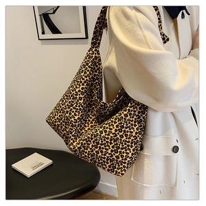 Detail of high-capacity leopard print tote bag in soft canvas worn with cream coat