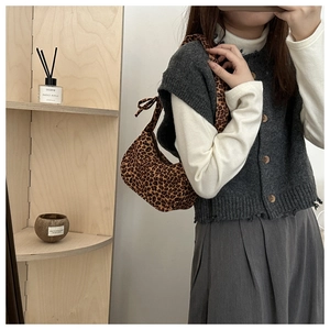 Detail of leopard print baguette shoulder bag styled with grey knit vest and pleated skirt