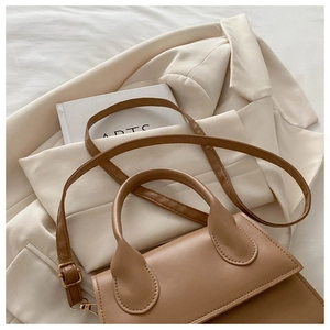 Detailed view of camel leather handbag with gold buckles and minimalist stitching details