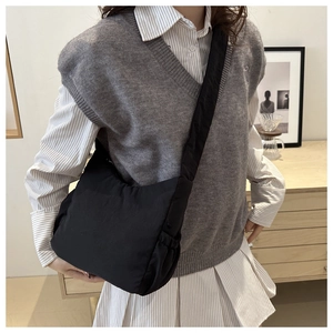 Detail of black pleated shoulder bag showing soft nylon texture and drawstring craftsmanship