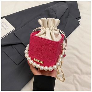 Detail of rose pink handbag with floral lace embossing, pearl handle and chain strap