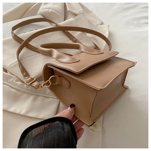 Detail of a chic beige leather handbag with gold hardware and structured top handle