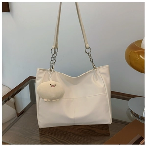 Detail of cream white tote bag with cross-stitch design and silver chain shoulder strap