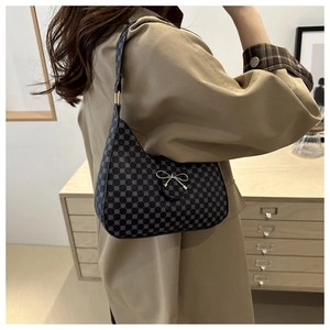 Detail of vintage bow shoulder bag with geometric patterns worn by a model in a trench coat