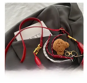 Close-up of wine red glossy leather tote bag with gold buckle and plush bear charm
