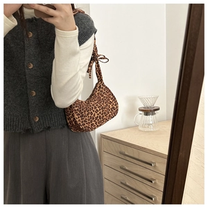 Detail of leopard print baguette bag with a decorative bow on the shoulder strap